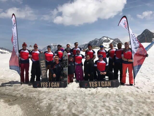 Group of people in red snowsuits on snowy mountain