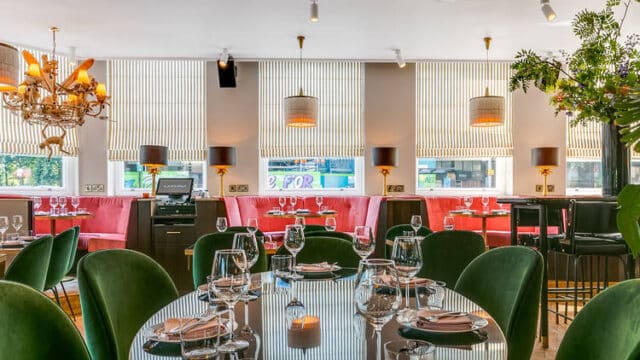 large room with pink and green chairs around tables